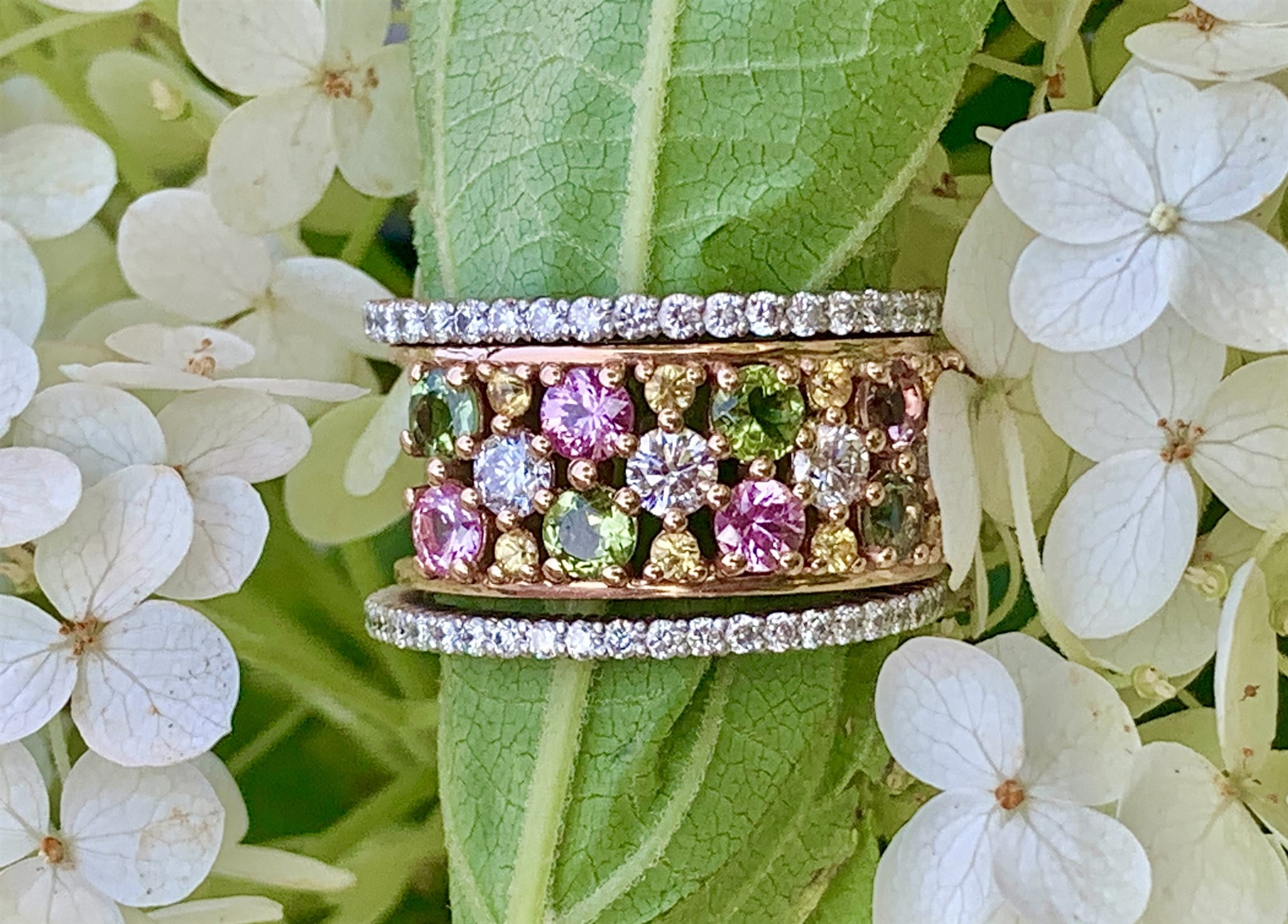 Multicolored ring with eternity band on green leaf.jpg